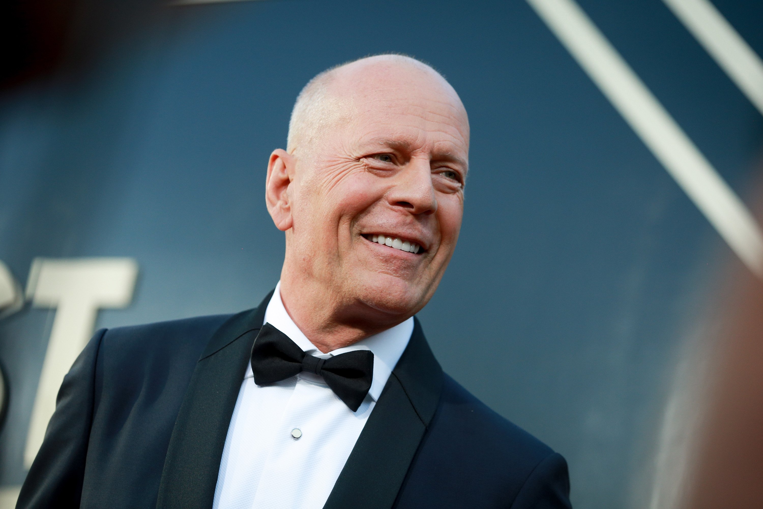 Bruce Willis in a black suit and bowtie.
