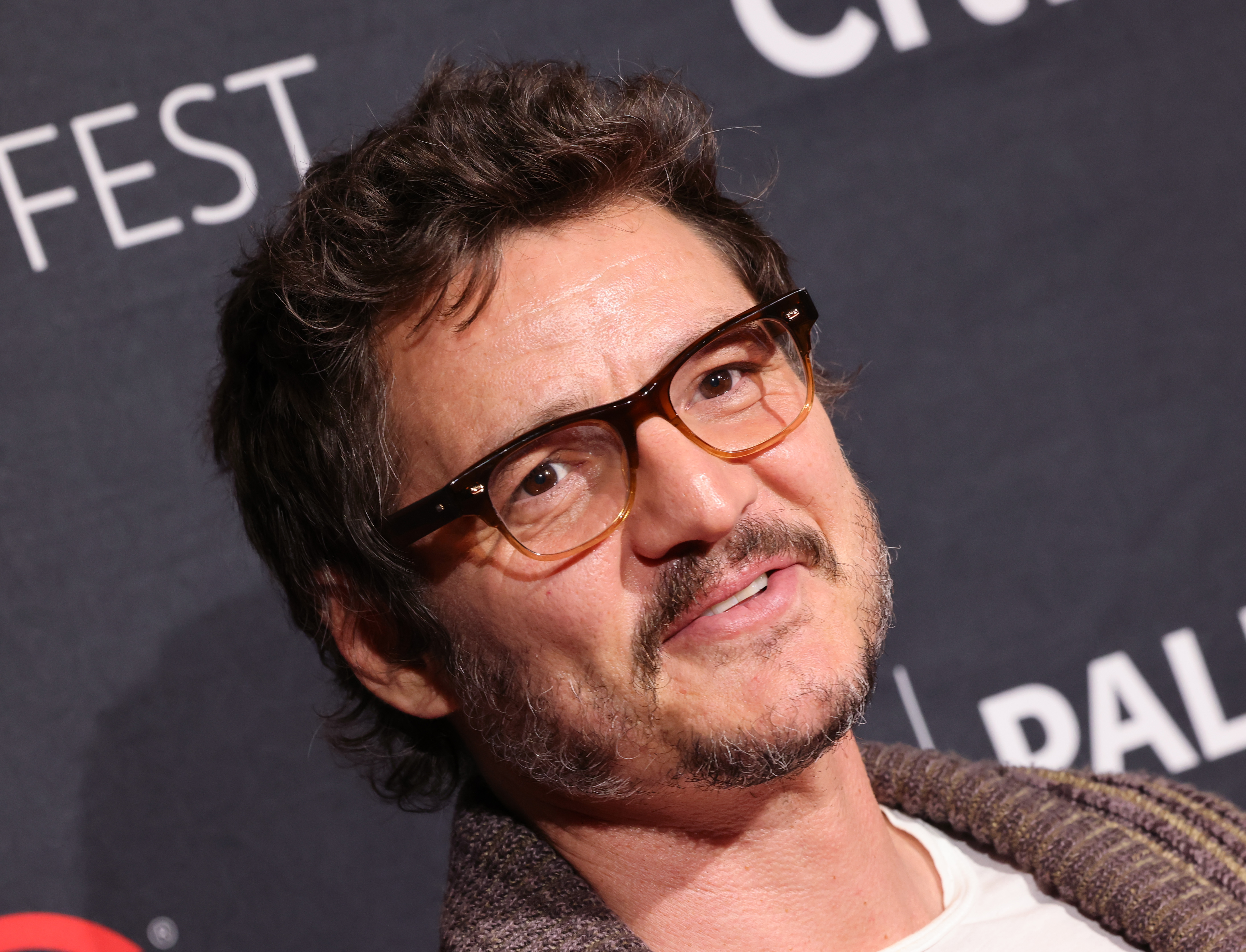 Pedro Pascal in glasses and a brown cardigan.