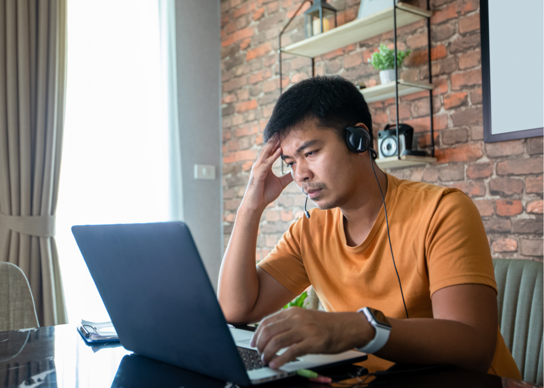 A serious looking man reads information on his laptop.