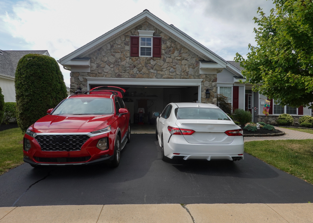 Twoc cars in front of a suburban home.