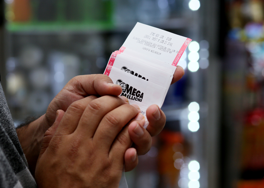 A person holding Mega Millions tickets.