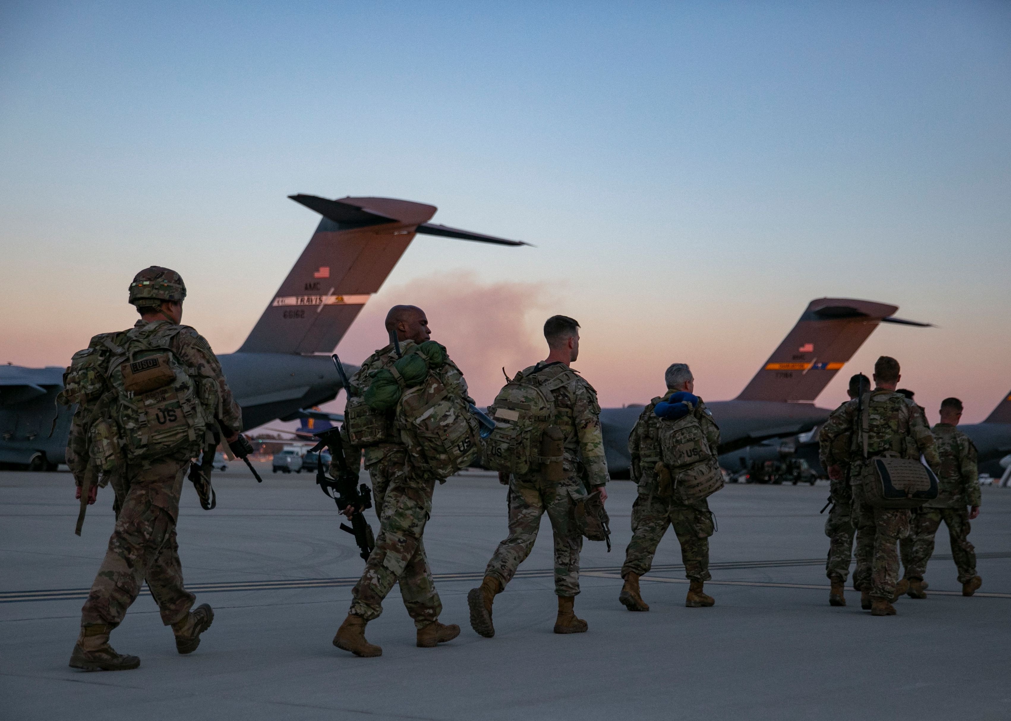 Soldiers of the 82nd Airborne Division walk to board a plane.