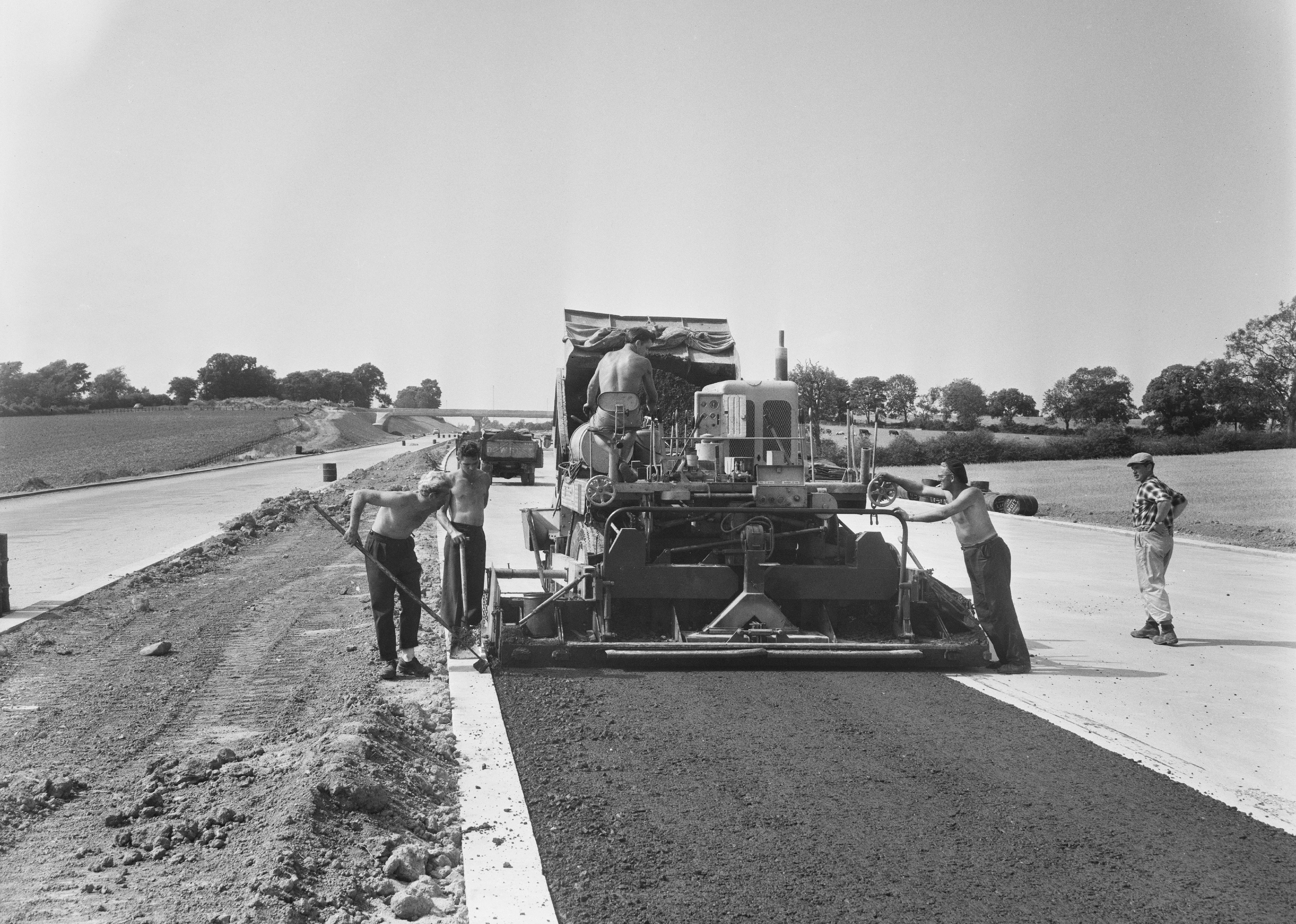 A view of Laing workers operating a paver machine, laying an asphalt base.