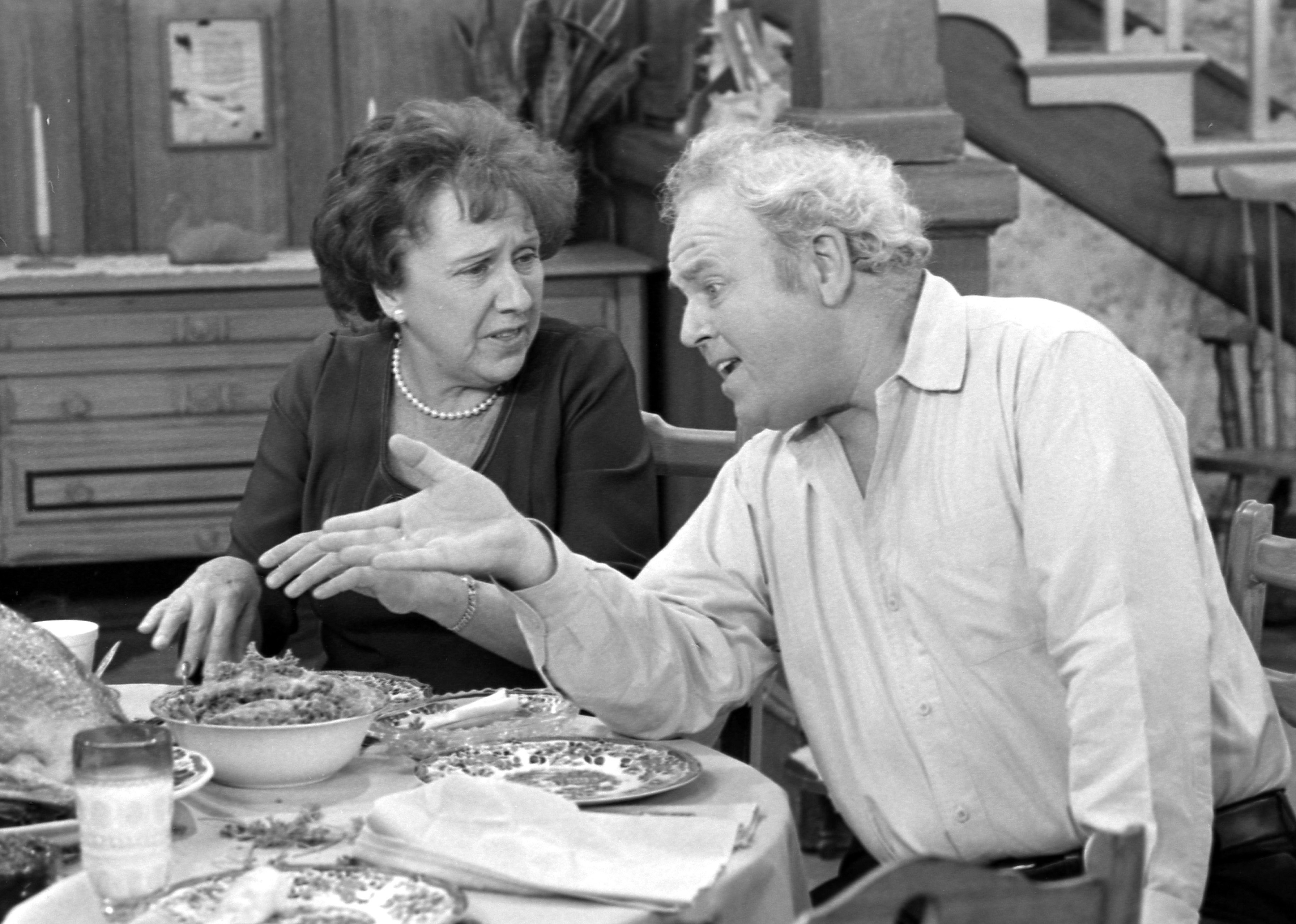 Carroll O'Connor and Jean Stapleton talking at the dinner table on the set of All in the Family.