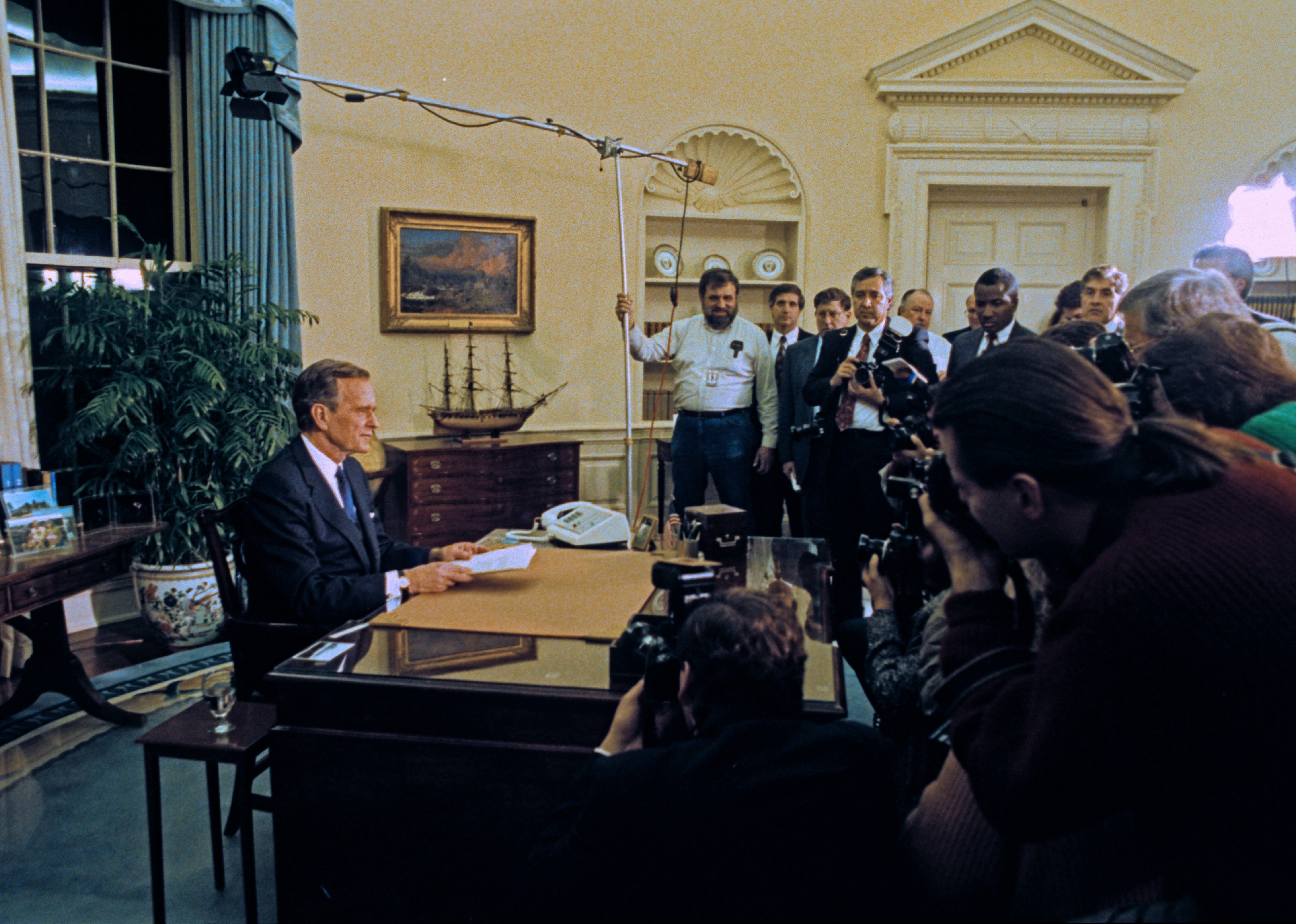 President George HW Bush sits behind his desk in the White House's Oval Office.