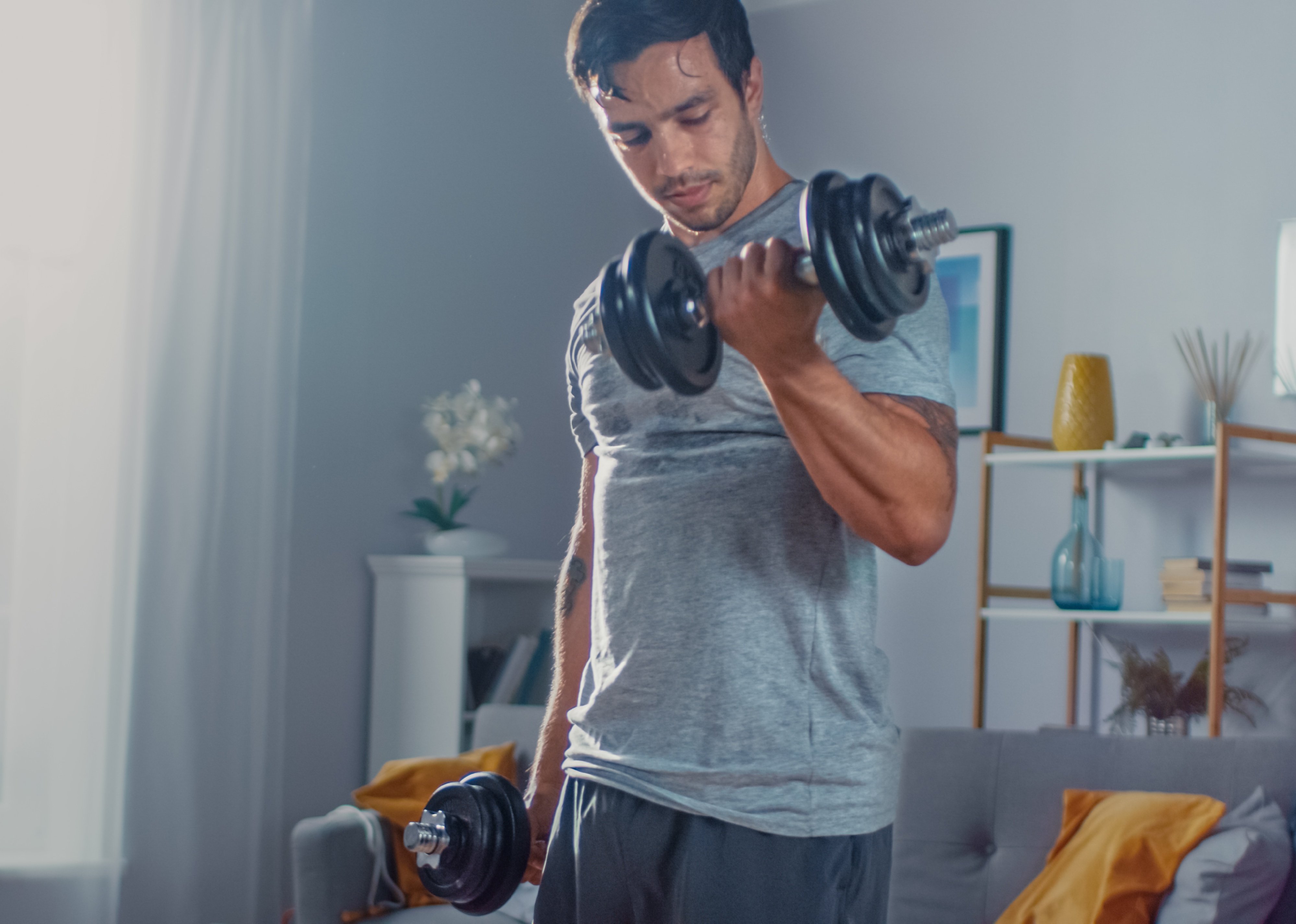 Man doing exercises with dumbbells at home.