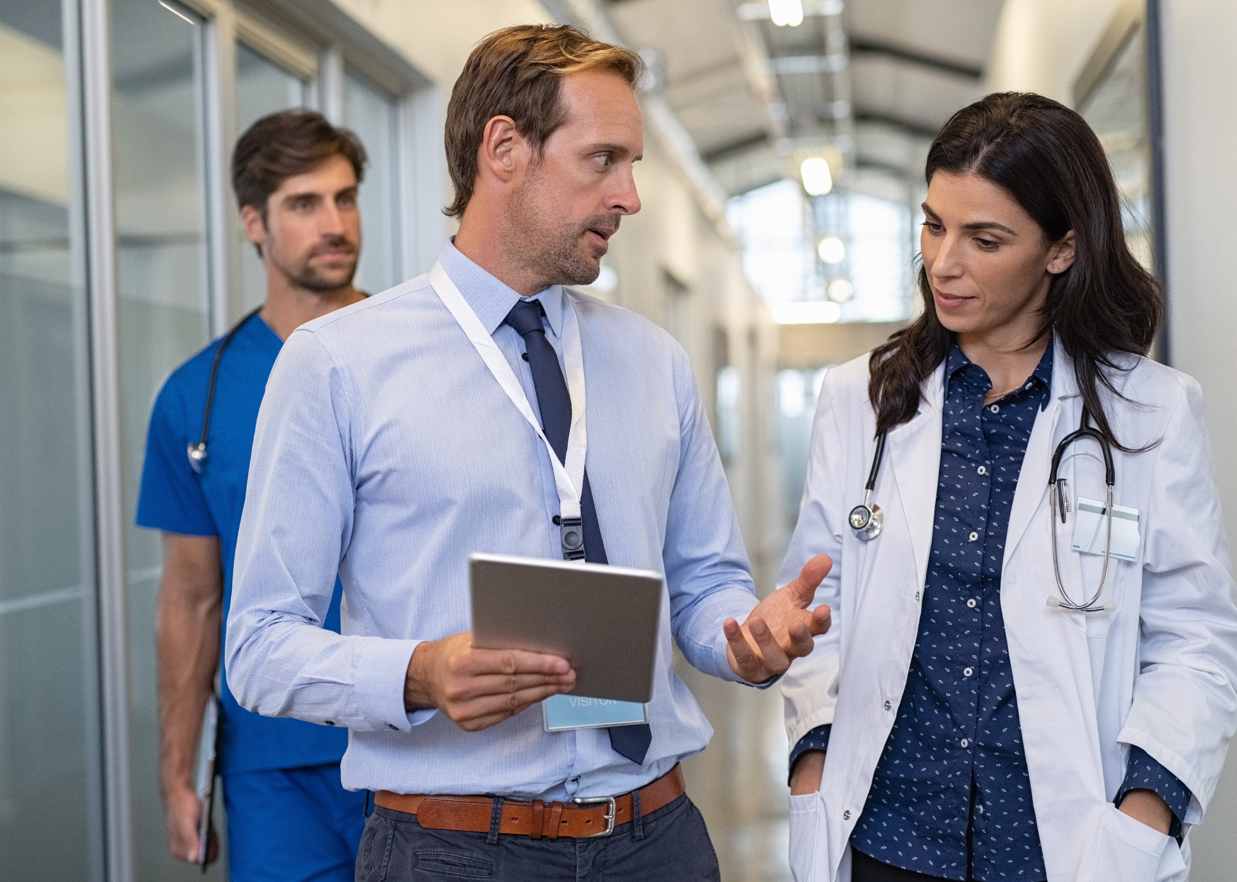 Male and female doctor having a discussion in hospital hallway.