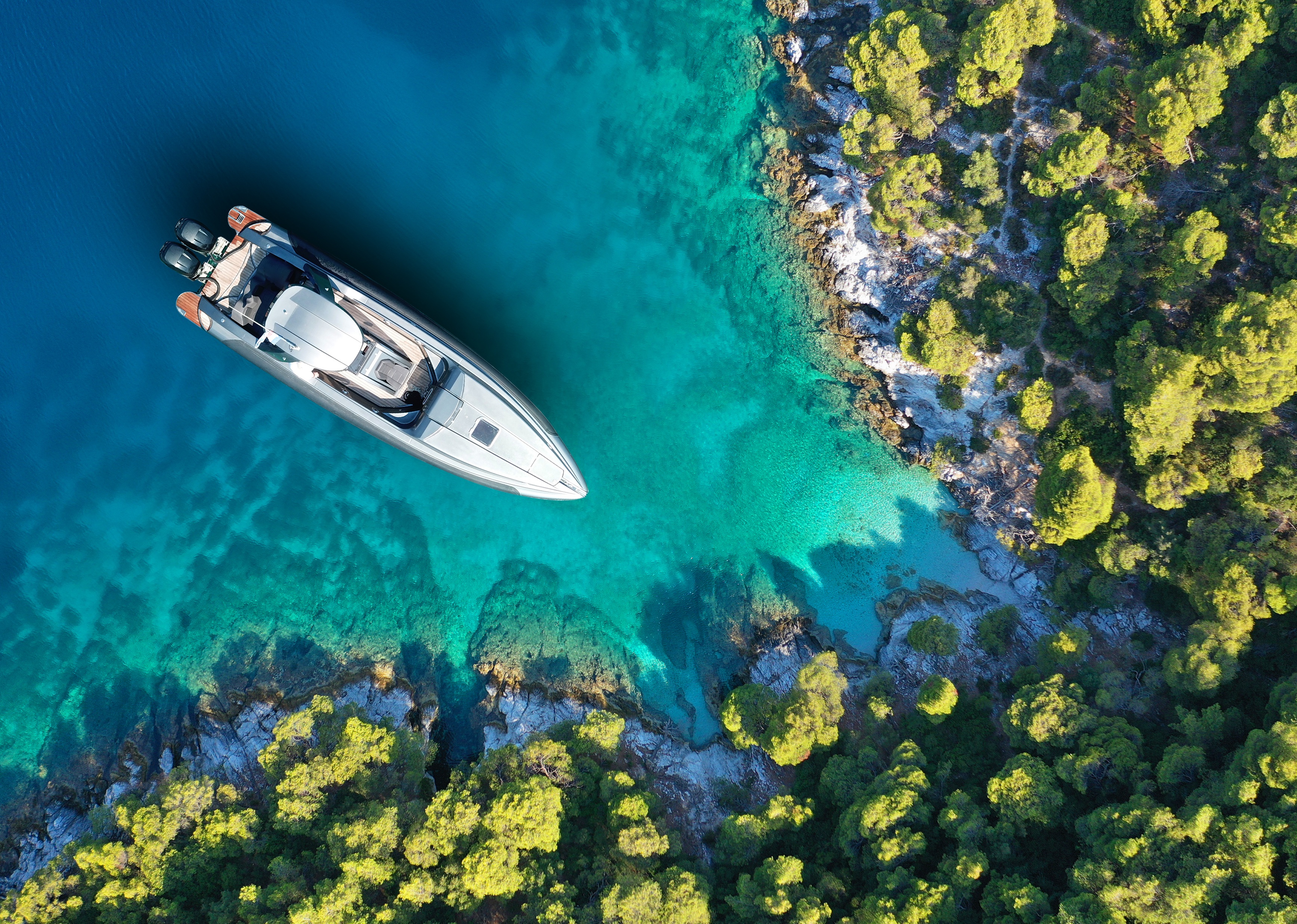 Aerial drone top down photo of inflatable speed boat anchored in tropical island.