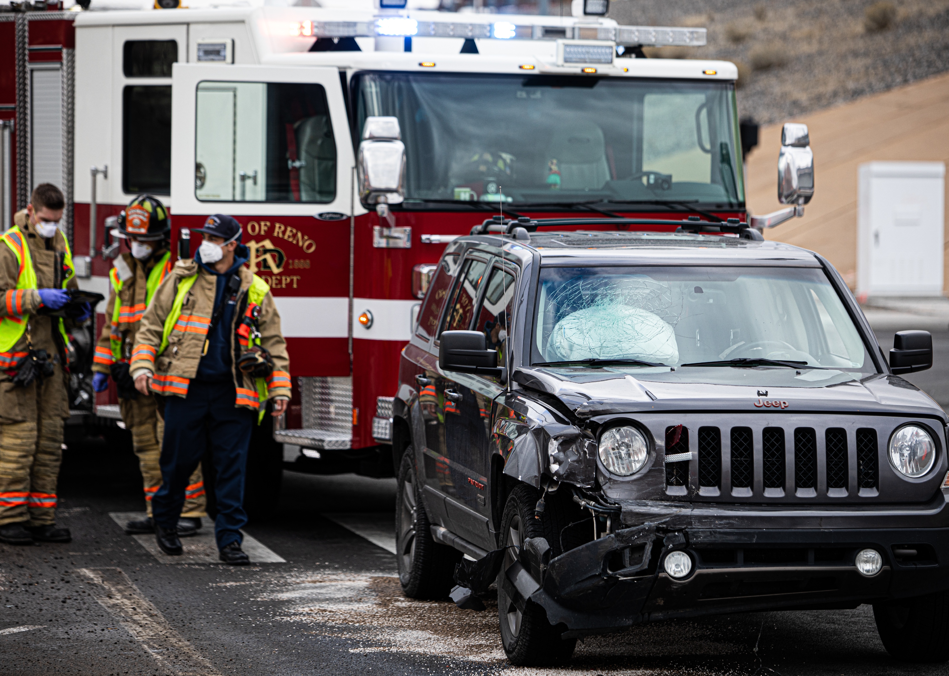 A vehicle crash on the side of the freeway including a black jeep as firefighters assess the damage.