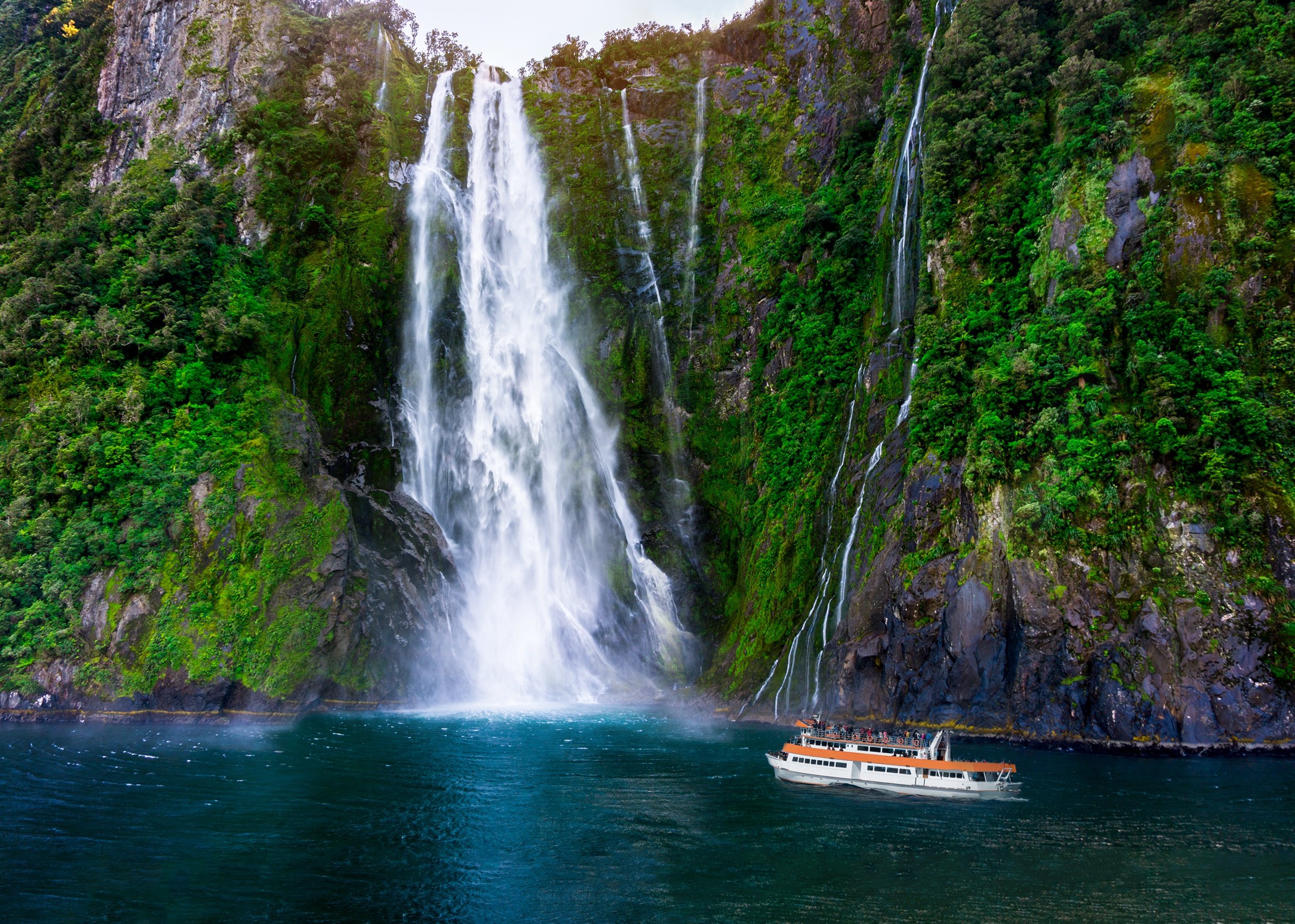 Tourist ferry approaching Stirling Falls at Milford Sound in South Island.