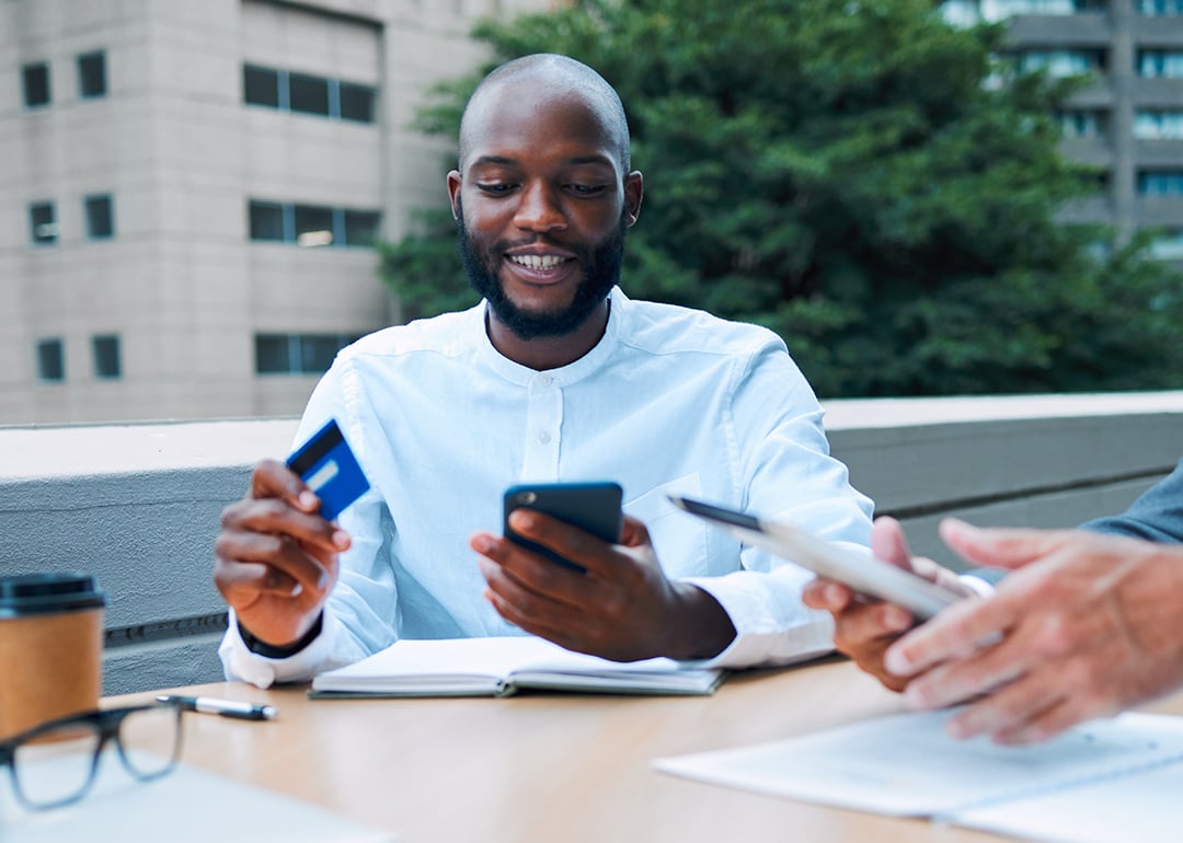 A young black businessman using a credit card to pay for a coffee shop transaction.