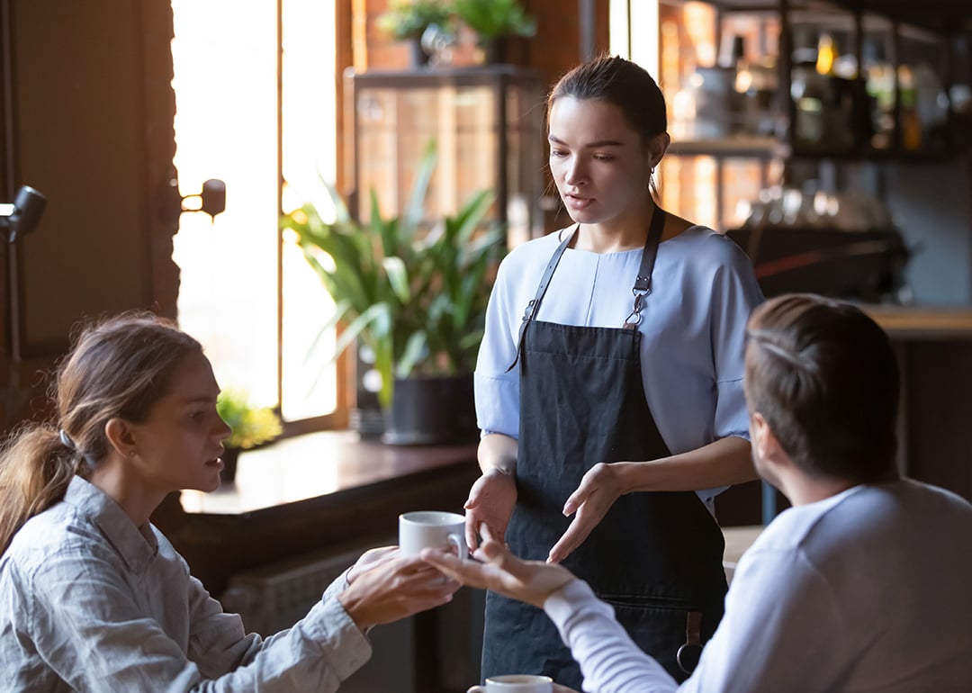 An angry couple disputing a complaint with a cafe waitress.