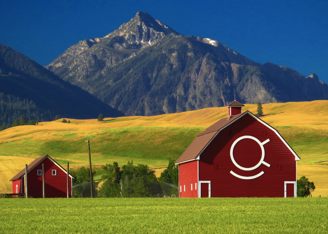 Red barn in field near Wallowa Mountains in Oregon.