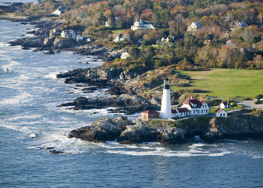 Rocky coastline with white houses and a lighthouse. 