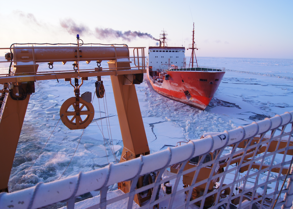 A tanker follows a coast guard boat in icy water.