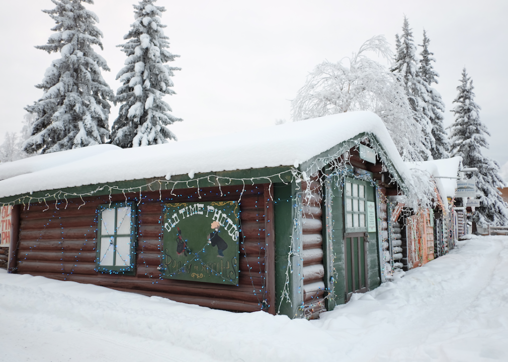 Snowy log cabins decorated with Christmas lights.