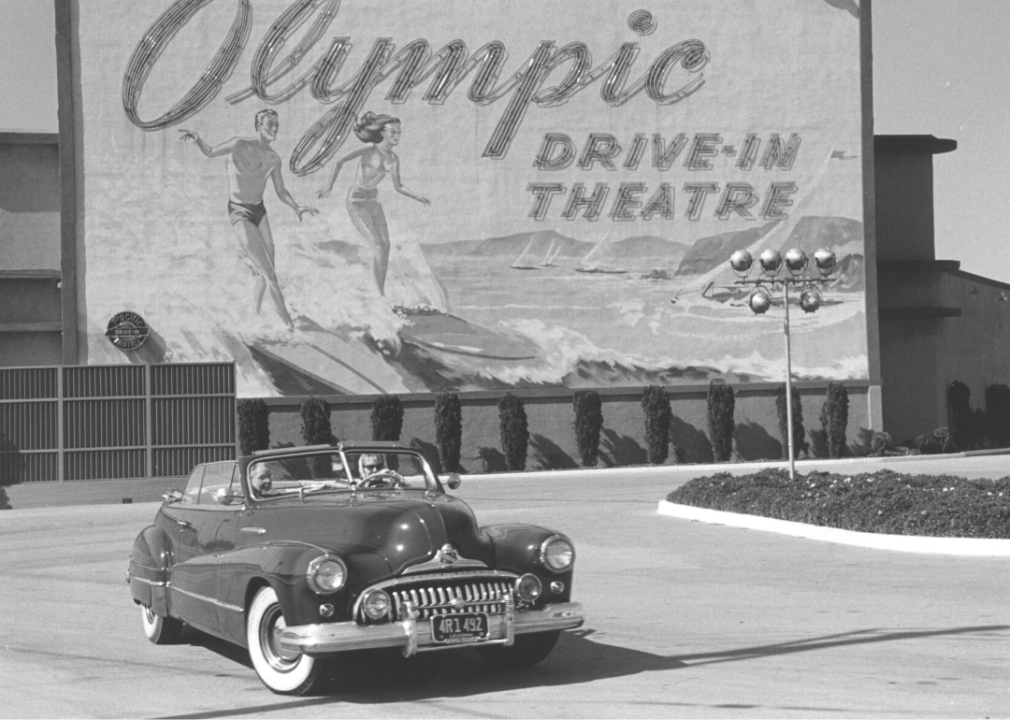 Convertible drives past Olympic drive-in theatre sign