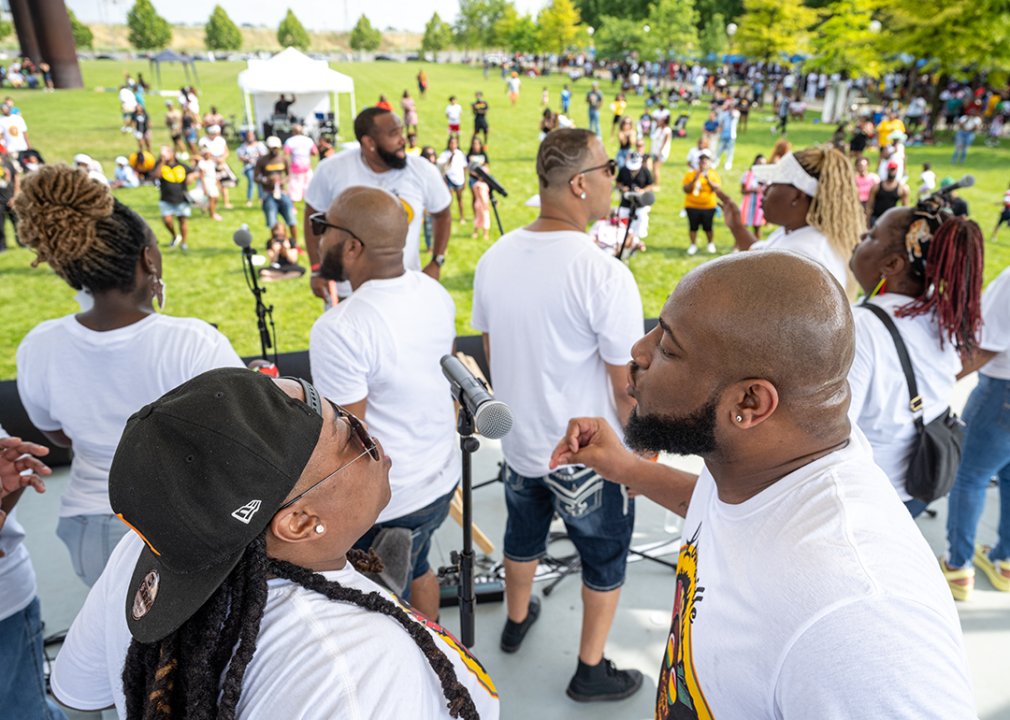 Two choir singers share a microphone during a performance at the Louisville Juneteenth Festival.