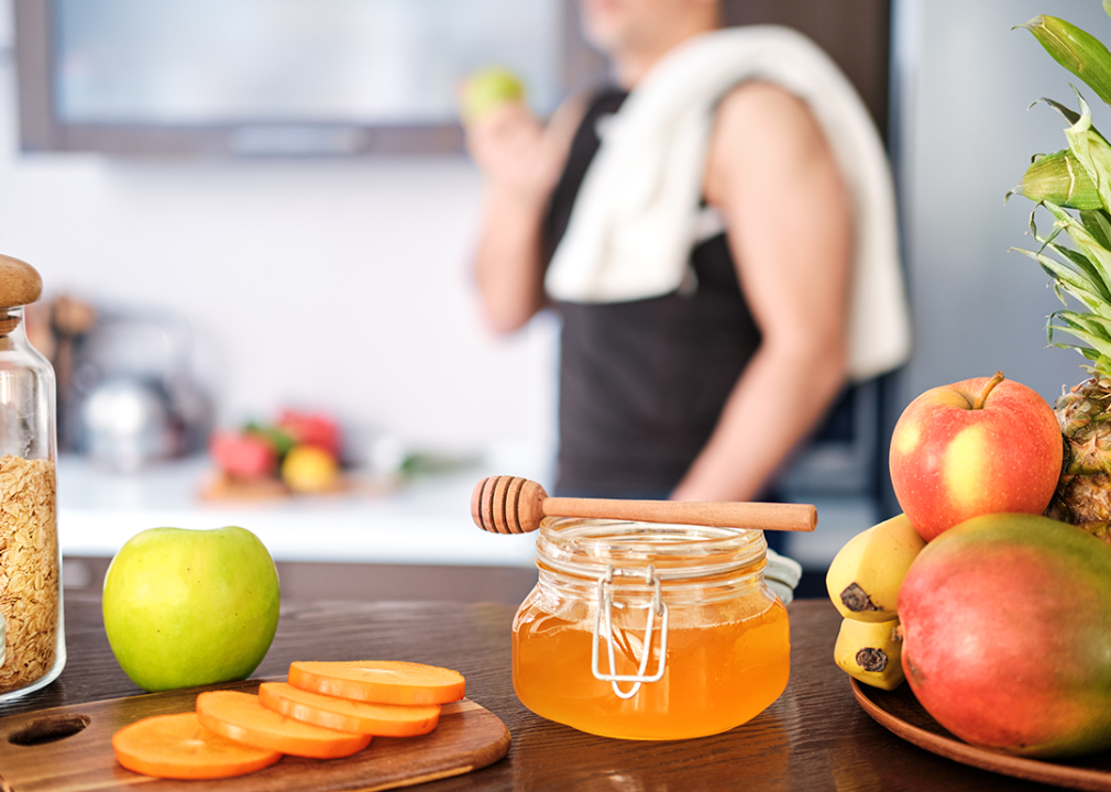 Man eating apple after exercise with honey in foreground.