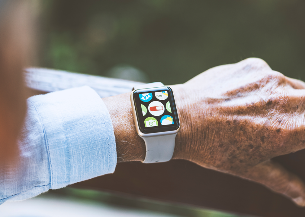 Older man wearing smartwatch medical pill reminder application icon on screen.