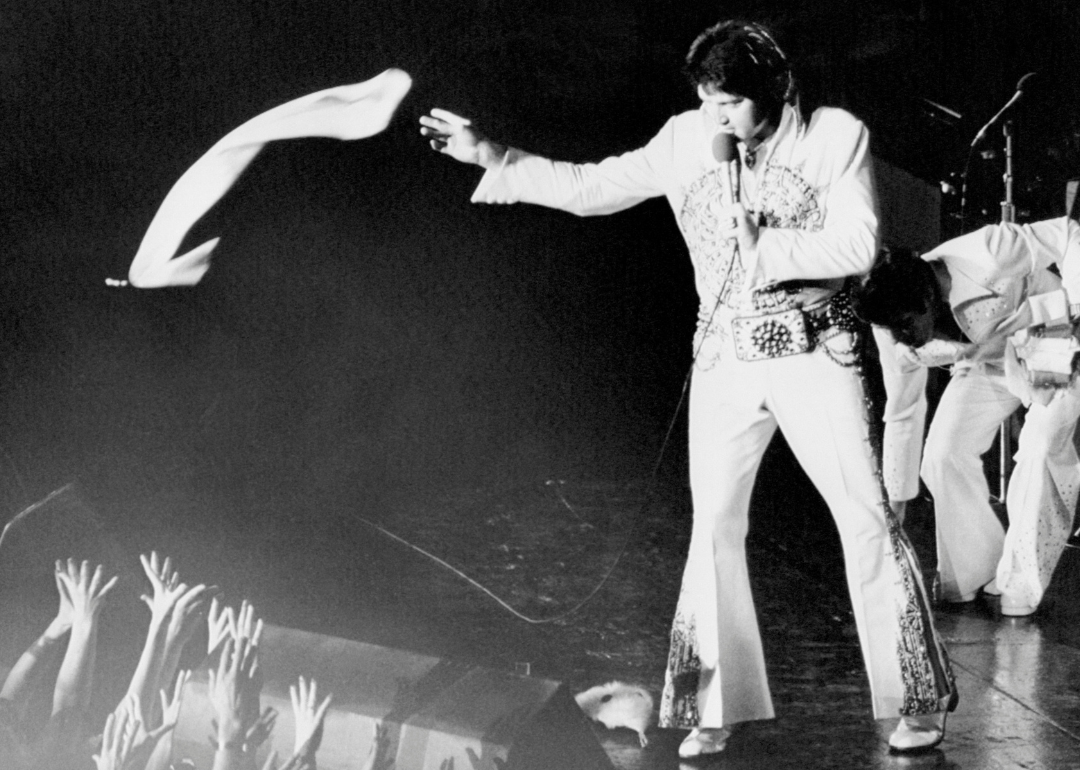 Elvis Presley tosses a scarf to fans during a performance.