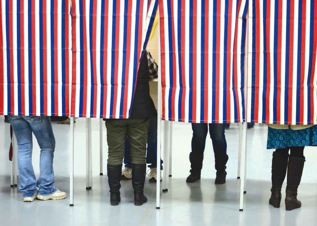 People standing in a row of voting booths