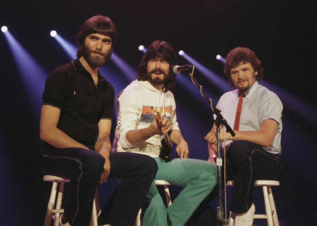 Randy Owen, Teddy Gentry and Jeff Cook of musical group Alabama pose on stools.