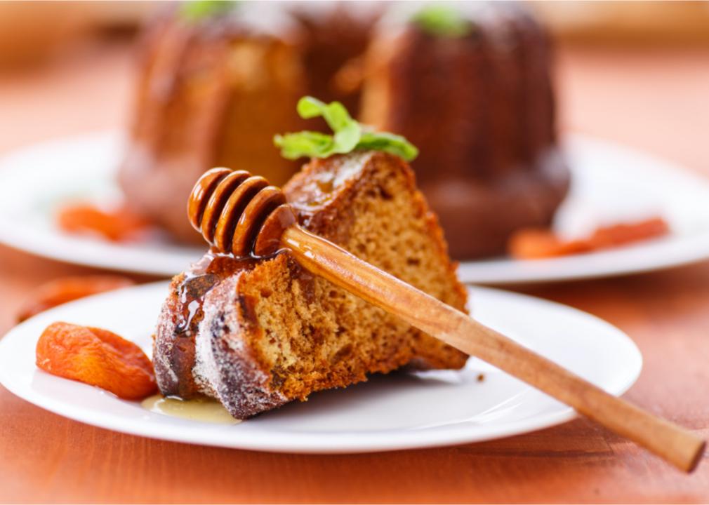 A slice of honey cake on a plate with a honey dripper. 