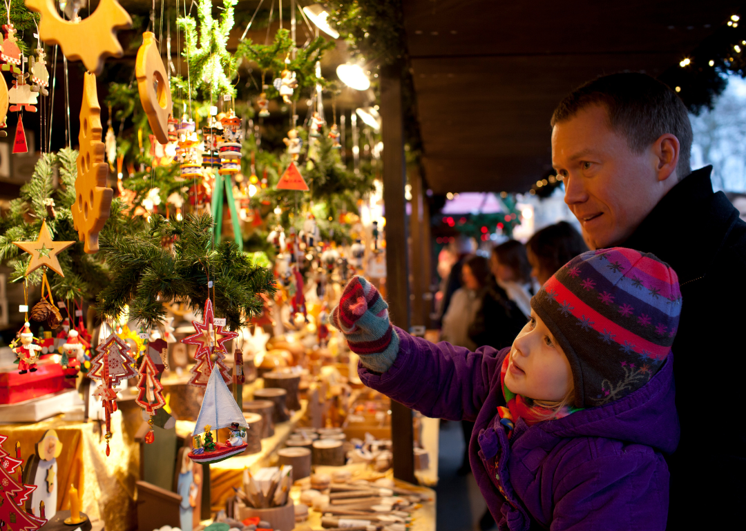 Parent and child shopping for Christmas ornaments at the Hyde Park Christmas market in London.