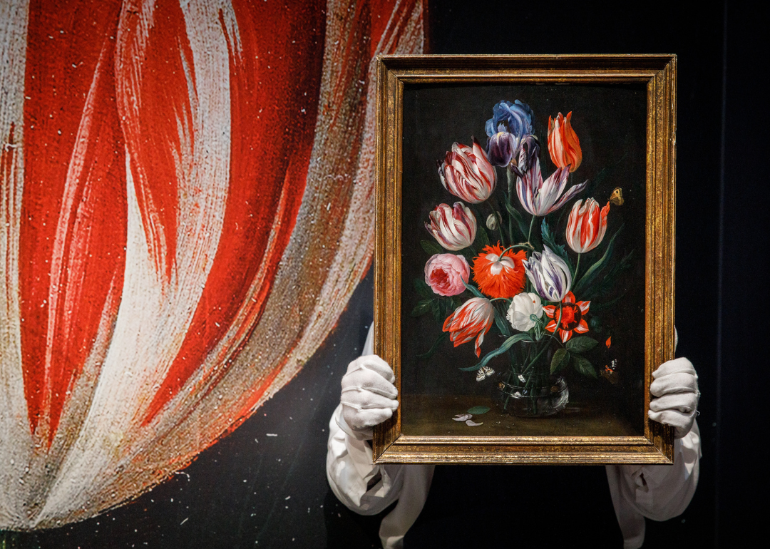 Still life of flowers in a vase by Jan van Kessel held by Sotheby’s attendant.