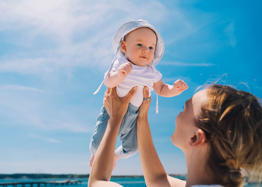 Holding baby up against blue sky.