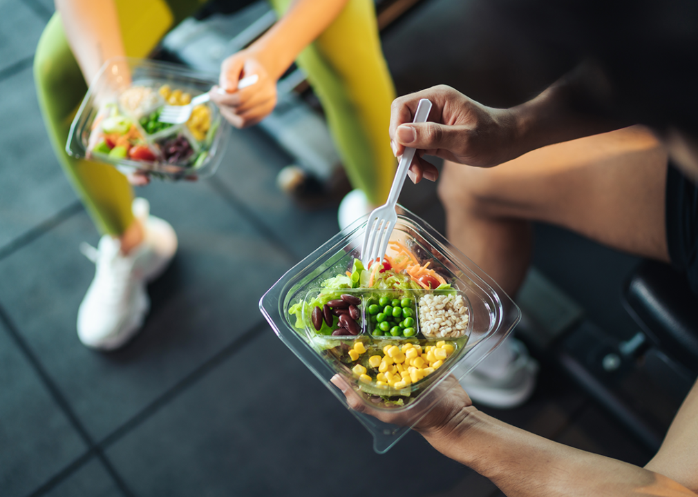 Two people eating salad at a gym.