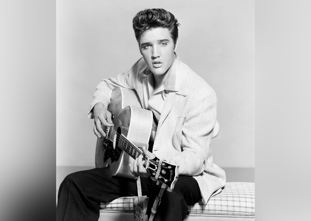 Elvis Presley poses for portrait with guitar.