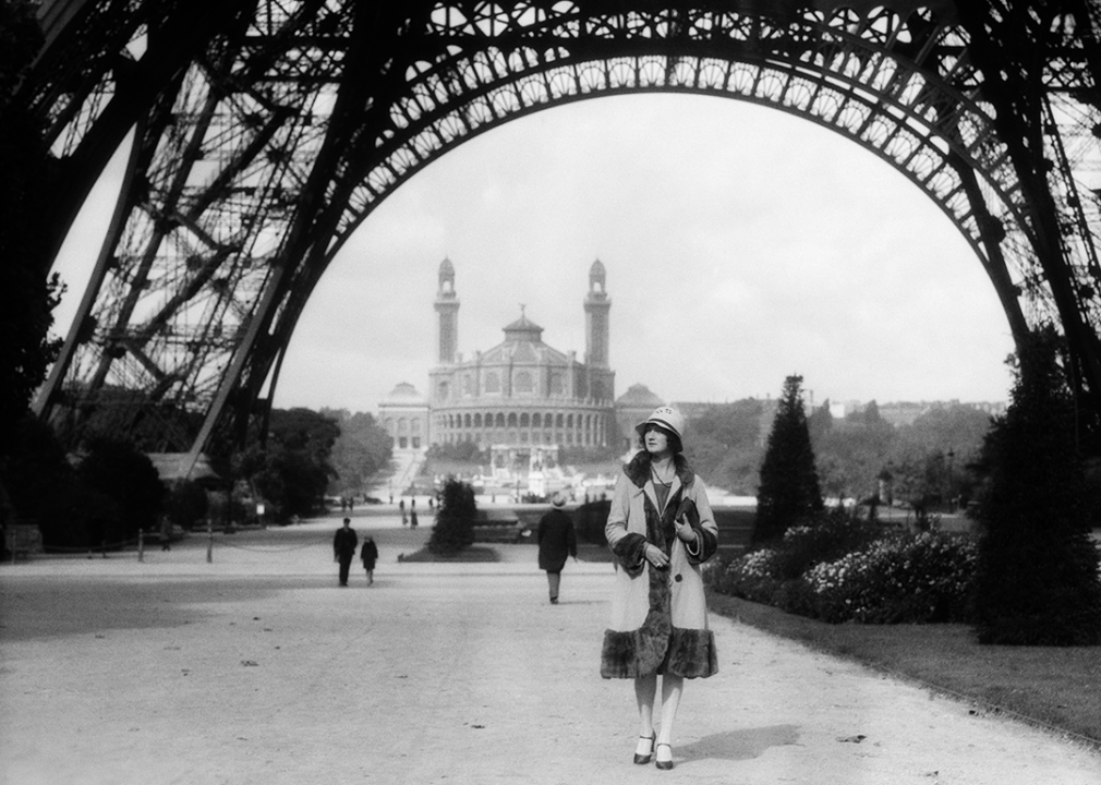 Woman walking under the Eiffel Tower with the Trocadero in the background.