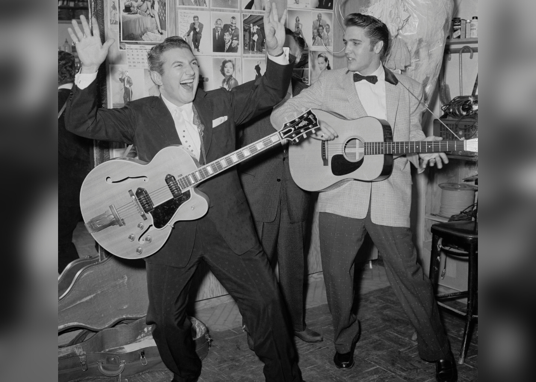 Liberace and Elvis Presley with guitars backstage at a night club.