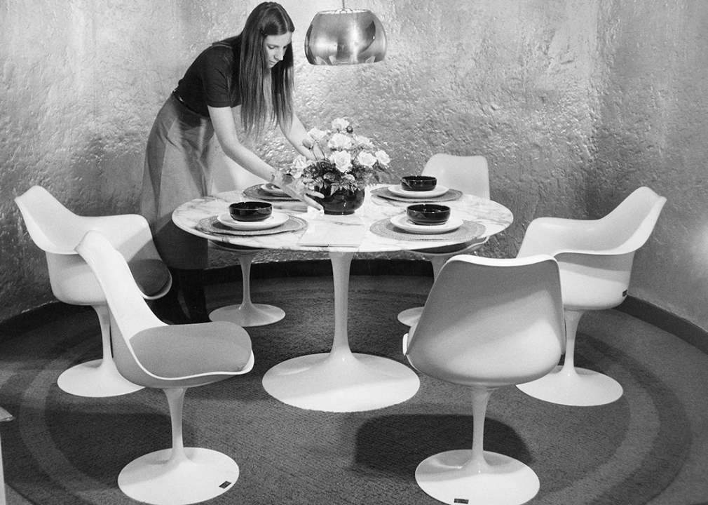 A woman places flowers on a Eero Saarinen tulip table.