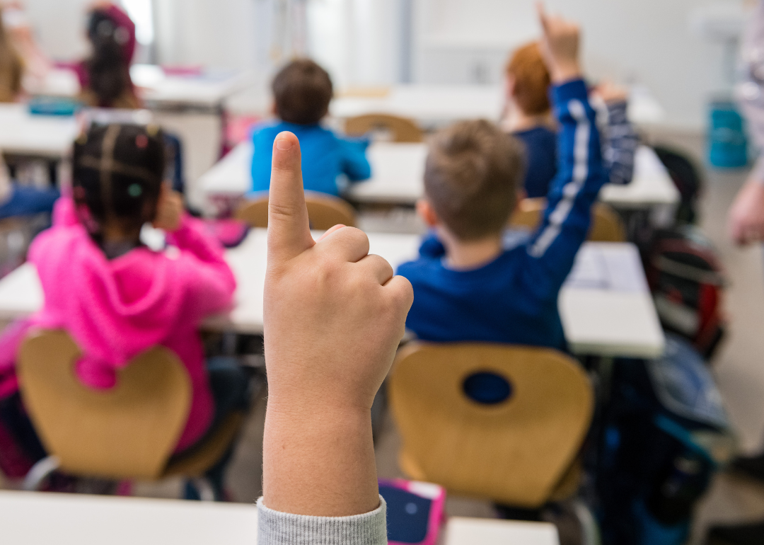 First graders raise hands in classroom