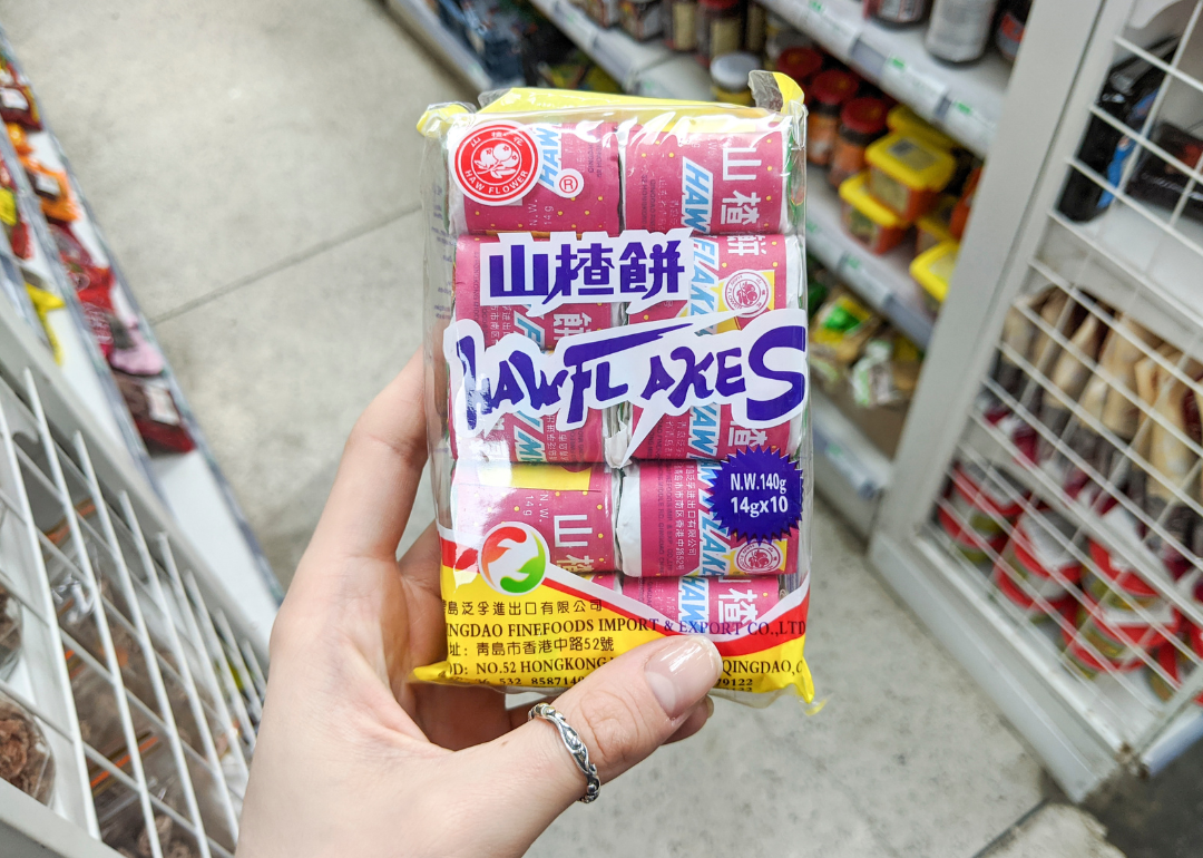 Hand holding package of Haw Flakes in supermarket.