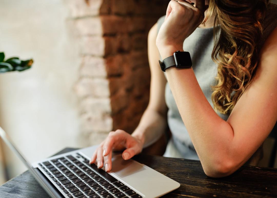 Person wearing smartwatch using laptop computer.