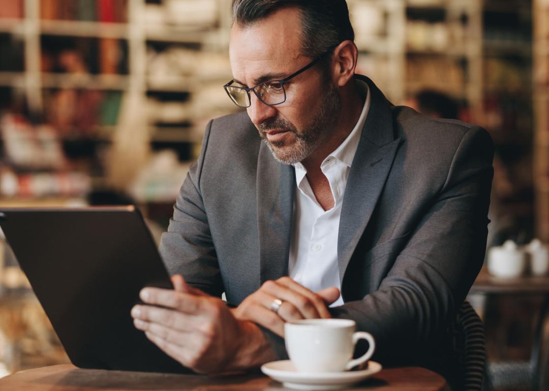 Man reading email on tablet in cafe.