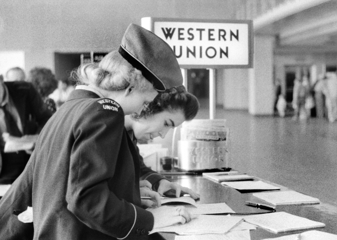 Two Western Union employees fill out paperwork