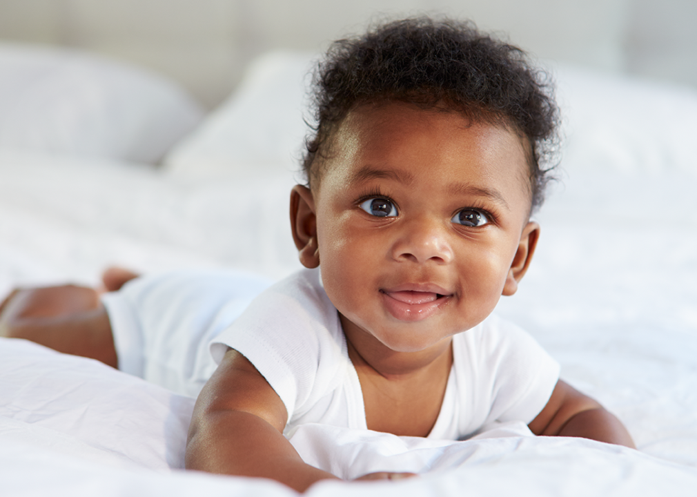 Portrait of baby on tummy in bed.