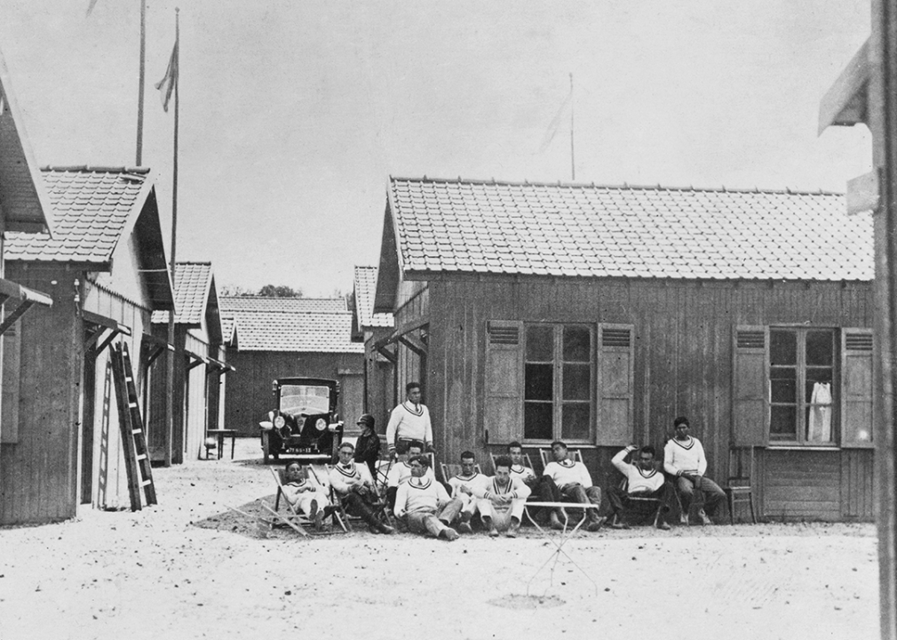 Athletes sitting in front of a cabin in the Olympic Village.