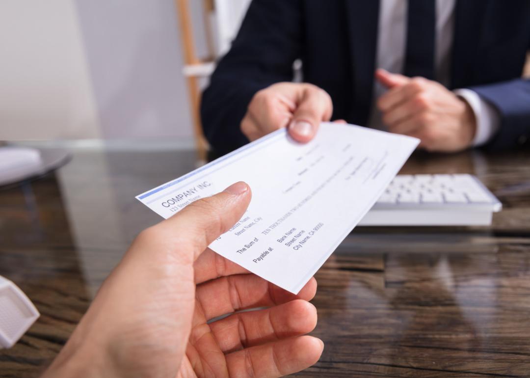 Businessperson handing check to employee.