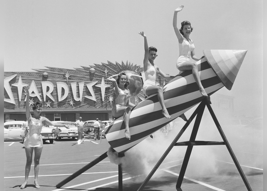 Para wanita berpose di atas penyangga roket di luar Stardust Resort.