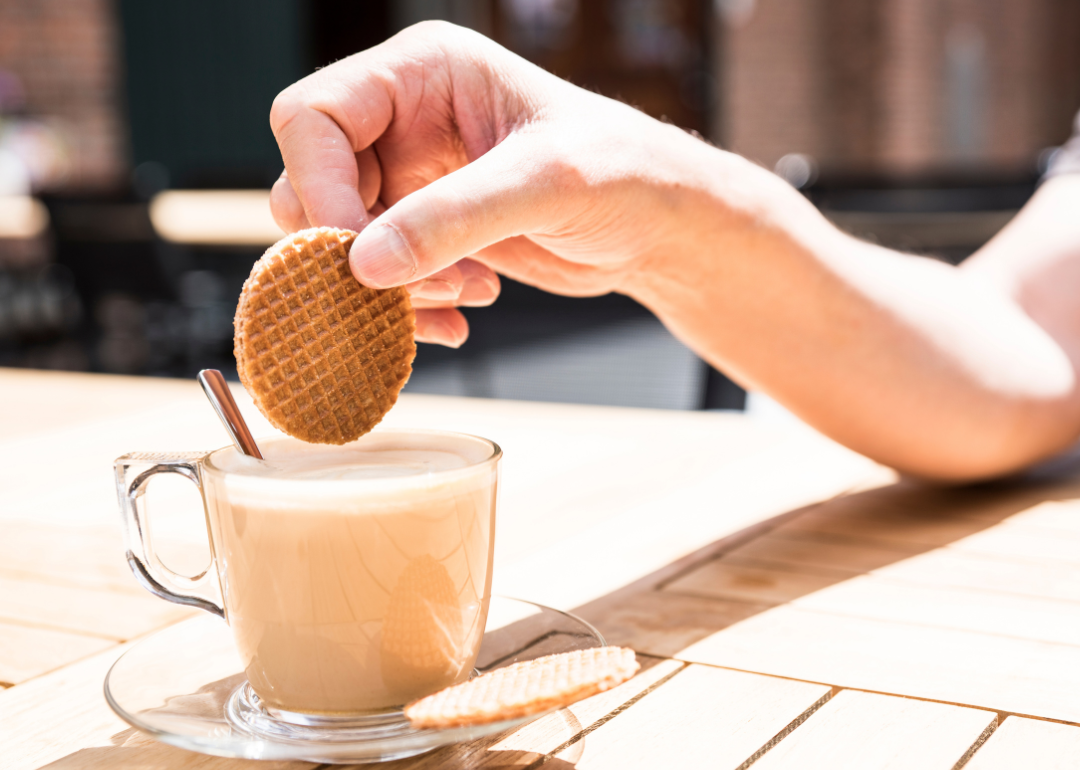 Person dipping stroopwafel in coffee.