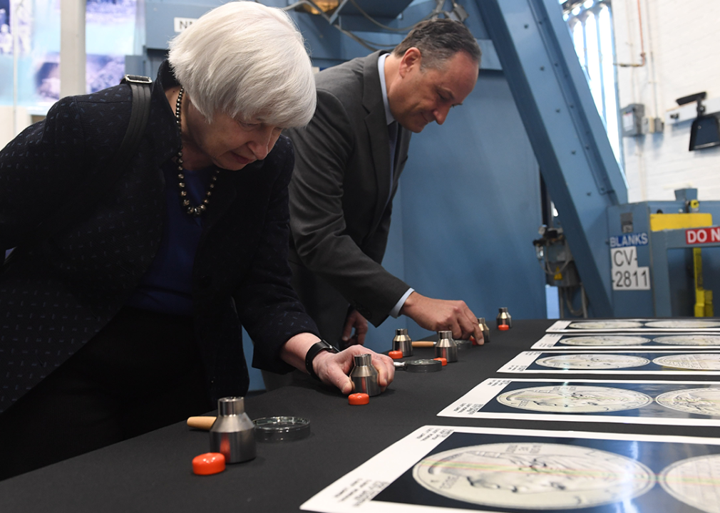 Janet Yellen and Douglas Emhoff inspect a series of dies used in the production of the new American Women Quarters Program.