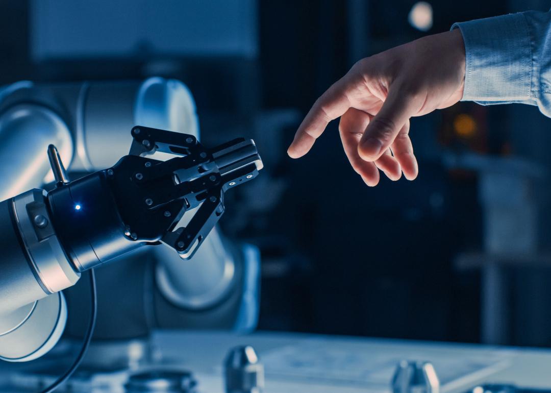 Futuristic robot arm touches human hand
