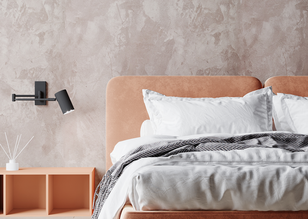 Bedroom with peach color headboard and plaster accent wall.