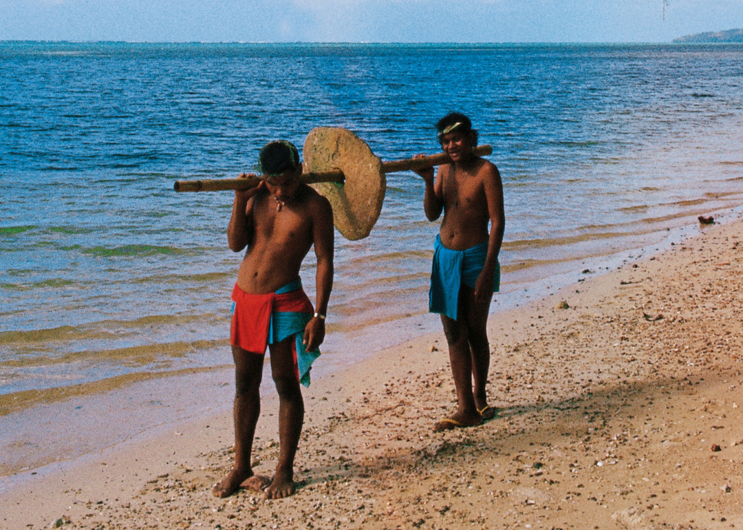 Men carrying an ancient stone coin on Yap Island.